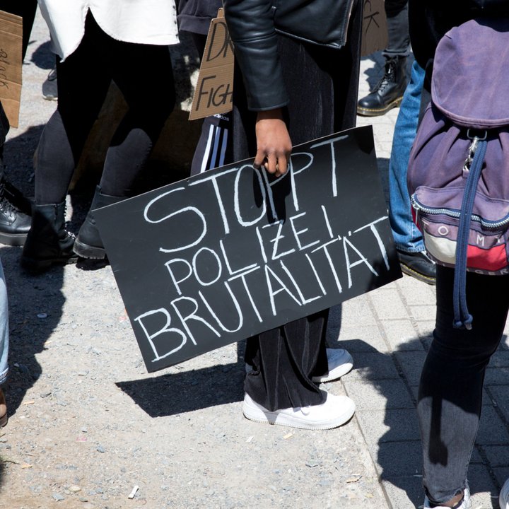 Eine Person hält ein Schild mit der Aufschrift Stoppt Polizeibrutalität