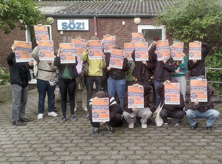 Eine Gruppe Menschen steht vor dem Söz und hält sich Essen widersetzt sich Plakate vor die Gesichter