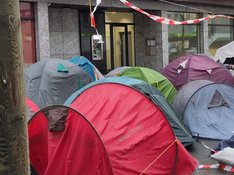 Foto einer Protestveranstaltung gegen die Vertreibung von Obdachlosen und Drogenkonsumierenden aus der Dortmunder Innenstadt mit aufgebauten Zelten neben der Sparkasse