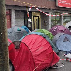 Foto einer Protestveranstaltung gegen die Vertreibung von Obdachlosen und Drogenkonsumierenden aus der Dortmunder Innenstadt mit aufgebauten Zelten neben der Sparkasse