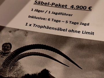 Bild eines Blattes auf dem in schwarz weiß das Angebot einer Trophäenjagd ausgedruckt ist. Unten it ein Bild von einer toten Großantilope mit riesigen Hörnern, daneben kniet ein Mann. Darüber steht: Säbel-Paket 4.900€ Inklusive 6 Tage - 5 Tage Jagd. 1 Trophäensäbel ohne Limit